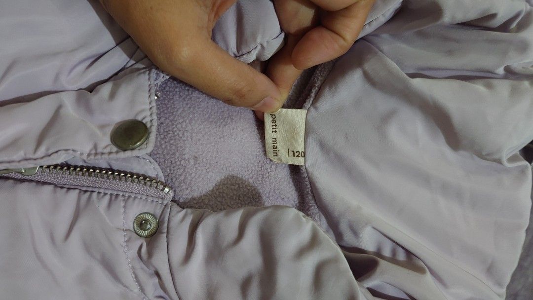Petit Main Purple Puffer Jacket Size 120 (Category: Babies & Kids Fashion) located in Pasig City. Submitted by m.eze (Listing ID 1470232570, Image 2). Description: - Brand/Model: Petit Main light purple puffer jacket - Size: 120 (tag inside) - Design: Quilted with a high collar and front pockets - Closure: Zipper and snap buttons down the front - Comfort: Soft and warm inner lining - Condition: Clean overall, great for chilly weather.