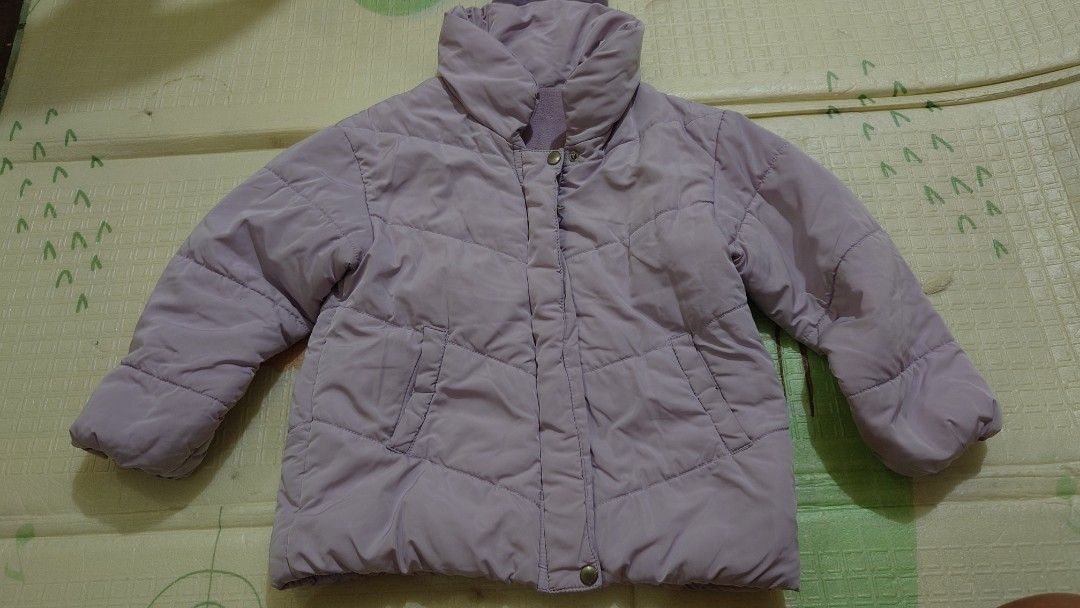 Petit Main Purple Puffer Jacket Size 120 (Category: Babies & Kids Fashion) located in Pasig City. Submitted by m.eze (Listing ID 1470232570, Image 1). Description: - Brand/Model: Petit Main light purple puffer jacket - Size: 120 (tag inside) - Design: Quilted with a high collar and front pockets - Closure: Zipper and snap buttons down the front - Comfort: Soft and warm inner lining - Condition: Clean overall, great for chilly weather.