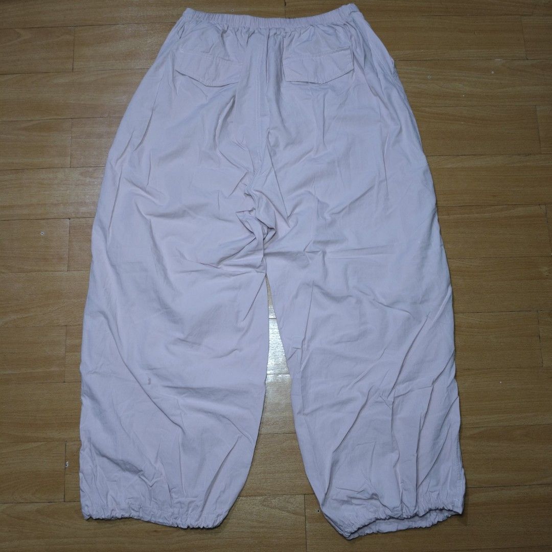 Pink Parachute Pants Wide Leg Drawstring Hem (Category: Jeans) located in Manila. Submitted by usedtobeyours26 (Listing ID 1470329391, Image 2). Description: - Color: Light pink - Fit: Comfortable elastic waistband, wide-leg design - Style: Techwear and streetwear aesthetic - Details: Layered front panels, two flaps back design - Feature: Adjustable drawstring toggles at the hems Disclaimer: Product Color May Slightly Vary Due to Photographic Lig