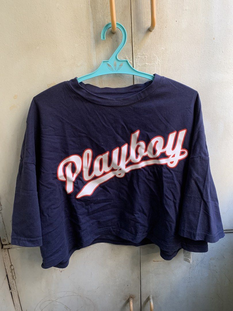 PLAYBOOK Crop T-Shirt (Category: Shirts) located in Manila. Submitted by usagichan_rabbit (Listing ID 1470145968, Image 1). Description: - Brand: PLAYBOY x Missguided collaboration - Color: Navy blue - Design: Large white and red script logo on chest - Fit: Cropped with relaxed drop-shoulder sleeves and crew neckline - Size: S (tag attached at inner collar) -Fit up to large -Super nice fabric 100% cotton.