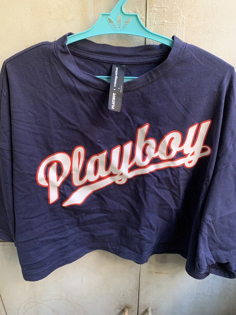 PLAYBOOK Crop T-Shirt (Category: Shirts) located in Manila. Submitted by usagichan_rabbit (Listing ID 1470145968, Image 2). Description: - Brand: PLAYBOY x Missguided collaboration - Color: Navy blue - Design: Large white and red script logo on chest - Fit: Cropped with relaxed drop-shoulder sleeves and crew neckline - Size: S (tag attached at inner collar) -Fit up to large -Super nice fabric 100% cotton.