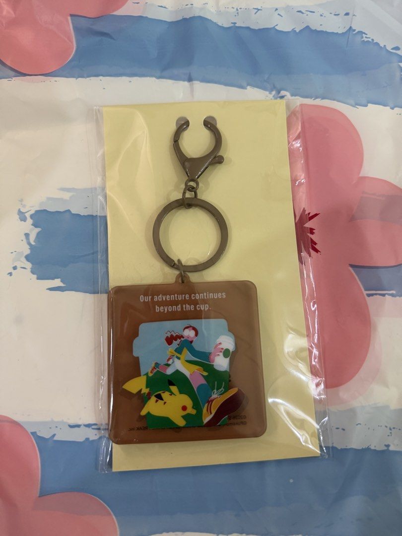 Pokémon Starbucks Special Edition Keychain (Category: Character Goods) located in Valenzuela. Submitted by sel000 (Listing ID 1470206117, Image 1). Description: - Official Starbucks x Pokémon collaboration keychain - Square brown design featuring Pikachu and a coffee-drinking character - Inspiring text: "Our adventure continues beyond the cup" - Durable metal keyring and clasp attached - Brand new, still sealed in original plastic packaging with 