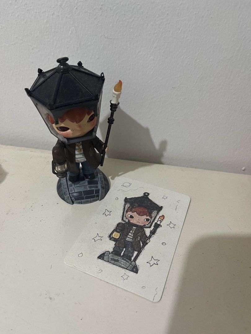 Pop Mart Hirono with Character Card (Category: Designer & Blind Box Toys) located in Pasig City. Submitted by chloe_miel (Listing ID 1470270251, Image 1). Description: - Authentic Pop Mart Hirono designer toy figurine - Features a striking black lamp shade hat, candle staff, and small lantern - Includes the matching illustrated character card - Stands on a detailed cobblestone textured base - Must-have addition to any designer toy collection.