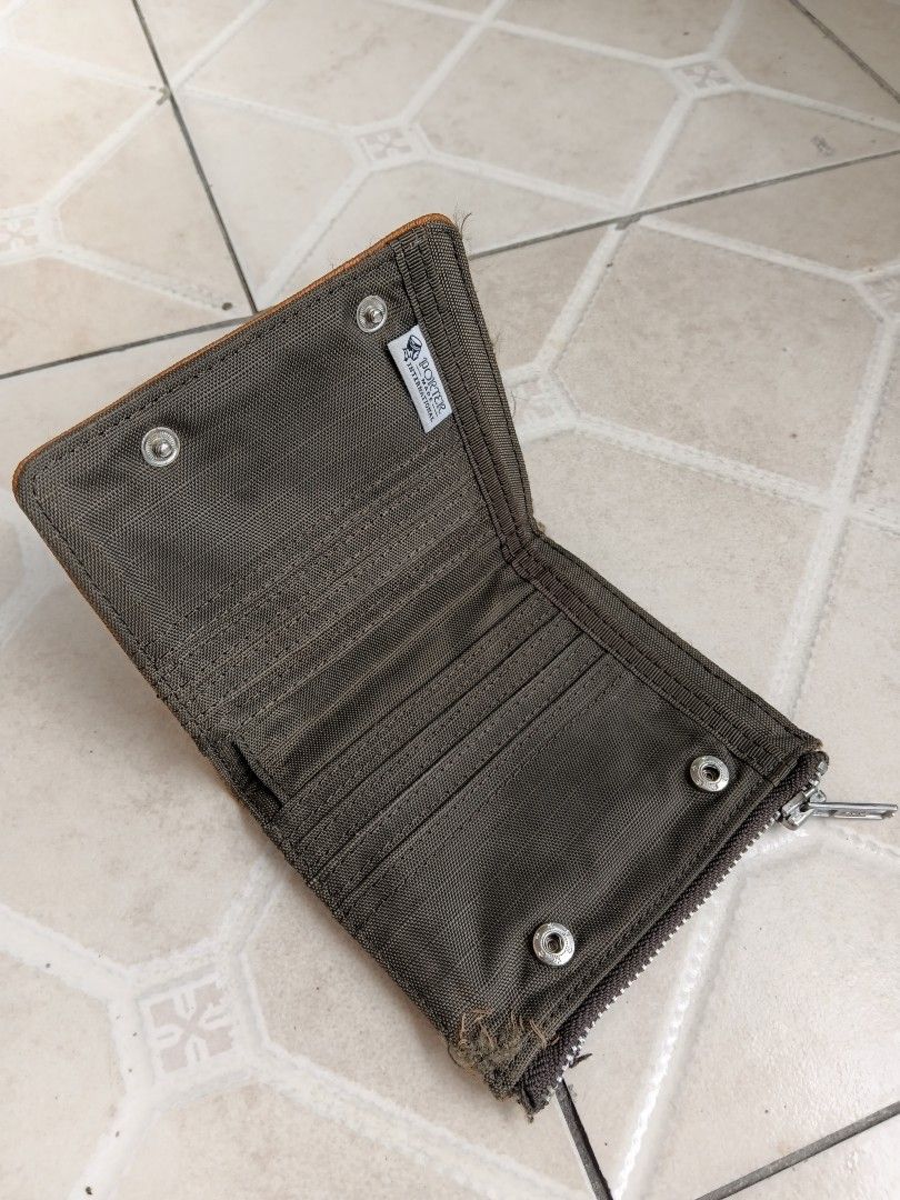 Porter International Bifold Wallet Brown Canvas (Category: Wallets & Card Holders) located in Manila. Submitted by grandflower-547aee (Listing ID 1470242650, Image 3). Description: - Brand: Porter International - Color/Material: Brown textured fabric - Closure: Secure snap button with exterior zip coin pocket on the back - Interior: Multiple card slots and slip compartments - Branding: Porter Made International woven label inside and front logo p