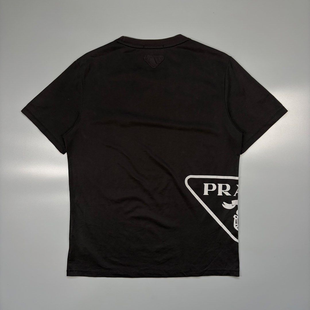 Prada Big Logo Reflectorized Logo Tee (OFF ONLY) (Category: Luxury Apparel) located in Cavite. Submitted by onebeancent (Listing ID 1470349072, Image 2). Description: (OFF ONLY / REFLECTORIZED SIDE PRINT) (Quickdry Material / Drifit) Size: Medium (Men) | XL (Women's) Dimension: 20" Width | 26" Length Color: Black Color Rate: 9/10 Issue: Slight Sunfade collar part Condition: Very good to Excellent Price: 780php Additional Shipping Fee (J&T Small P