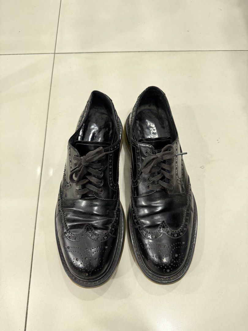 Prada Black Leather Brogues (Category: Dress Shoes) located in Bacolod City. Submitted by kitcarsonduff (Listing ID 1470190065, Image 1). Description: - Brand: Prada - Style: Classic black leather wingtip brogues with lace-up closure - Soles: Chunky rubber soles with traction tread pattern - Branding: Prada logo printed on the insole - Condition: Pre-loved with natural leather creasing and minor sole wear - Perfect for smart-casual wear, work, or