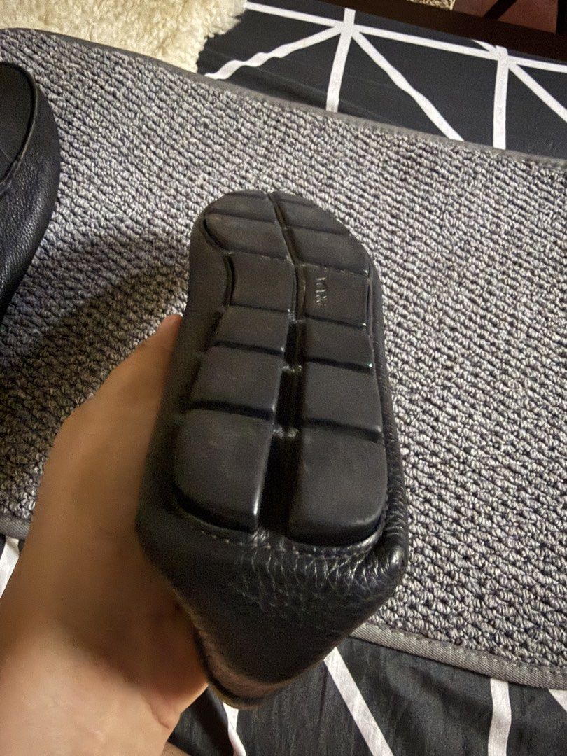 Prada Black Leather Driving Loafers (Category: Sneakers & Footwear) located in Manila. Submitted by patricio8717515 (Listing ID 1470187850, Image 3). Description: - Brand: Prada - Style: Slip-on driving loafers - Material: Black pebbled leather with tan leather inner lining - Details: Metal logo hardware on front strap, embossed Prada branding on sole - Sole: Flexible rubber pebble sole - Origin: Made in Italy - Condition: Clean soles with minima