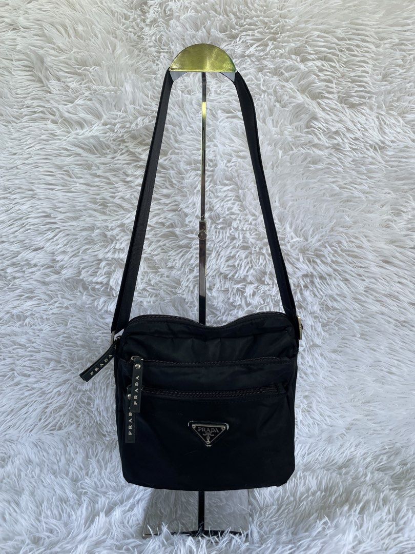 Prada Black Nylon Crossbody Bag (Category: Luxury Bags & Wallets) located in San Carlos. Submitted by jessamaep_deer (Listing ID 1470166232, Image 1). Description: - Authentic Prada crossbody bag in classic black nylon - Iconic silver triangular logo plaque on the front - Multiple exterior zipped compartments with branded rubber pull tabs - Secure main zipper with branded fabric interior lining - Features the classic silver "Prada Milano Made in 