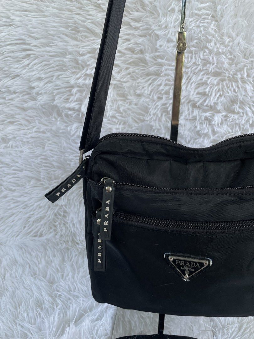 Prada Black Nylon Crossbody Bag (Category: Luxury Bags & Wallets) located in San Carlos. Submitted by jessamaep_deer (Listing ID 1470166232, Image 2). Description: - Authentic Prada crossbody bag in classic black nylon - Iconic silver triangular logo plaque on the front - Multiple exterior zipped compartments with branded rubber pull tabs - Secure main zipper with branded fabric interior lining - Features the classic silver "Prada Milano Made in 