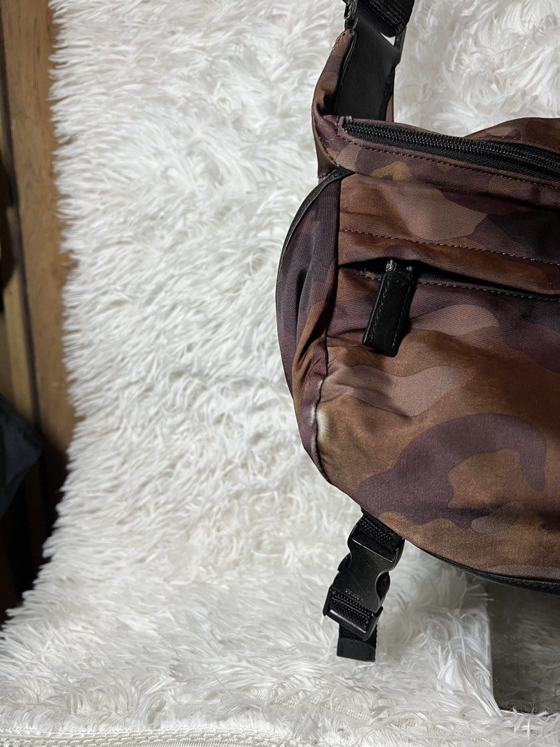 Prada Camouflage Nylon Crossbody Bag (Category: Luxury Bags & Wallets) located in San Carlos. Submitted by jessamaep_deer (Listing ID 1470271430, Image 2). Description: - Brand: Prada - Material: Camouflage nylon in stylish brown tones - Strap: Adjustable black shoulder strap with side release buckles - Pockets: Front zippered pocket and interior zip pocket - Details: Iconic enameled metal triangle logo and branded interior metal plaque - Conditi