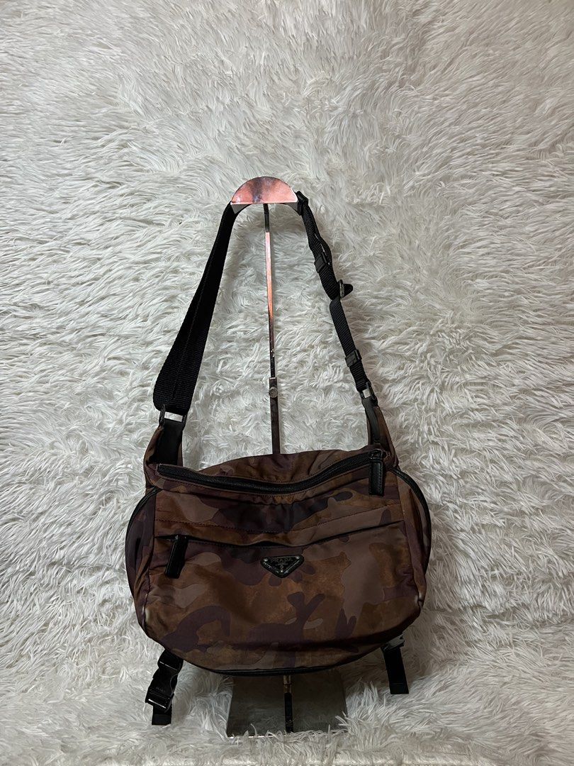 Prada Camouflage Nylon Crossbody Bag (Category: Luxury Bags & Wallets) located in San Carlos. Submitted by jessamaep_deer (Listing ID 1470271430, Image 1). Description: - Brand: Prada - Material: Camouflage nylon in stylish brown tones - Strap: Adjustable black shoulder strap with side release buckles - Pockets: Front zippered pocket and interior zip pocket - Details: Iconic enameled metal triangle logo and branded interior metal plaque - Conditi