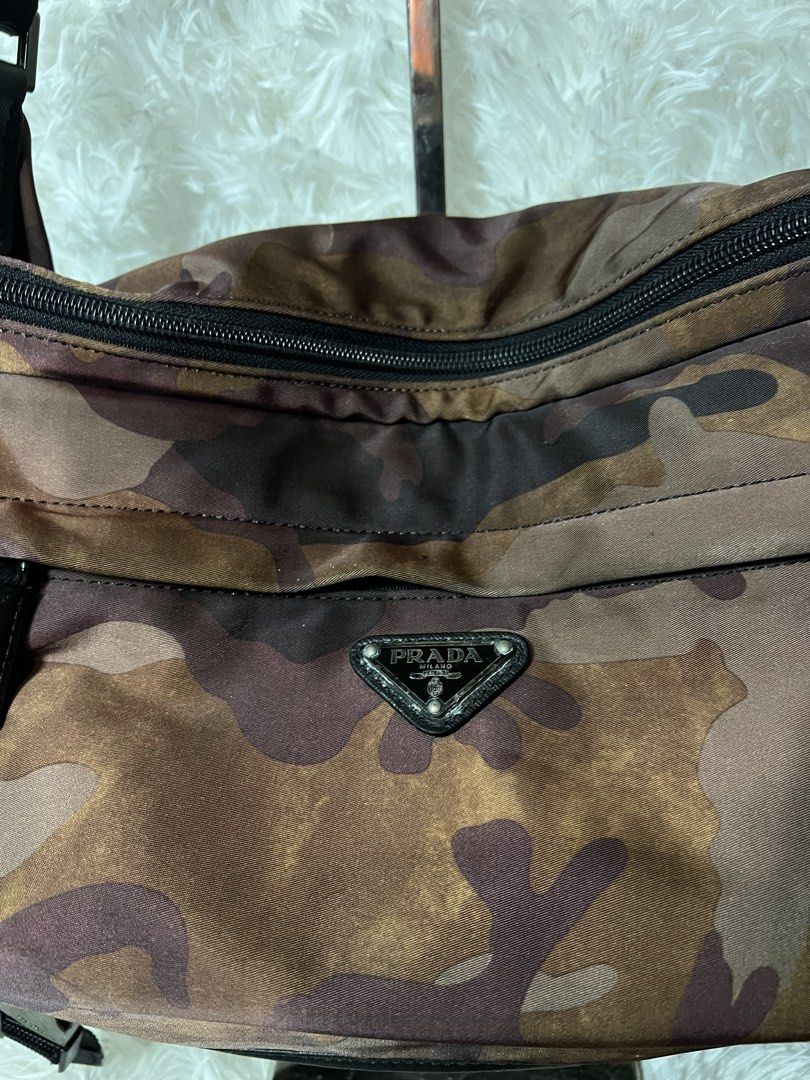 Prada Camouflage Nylon Crossbody Bag (Category: Luxury Bags & Wallets) located in San Carlos. Submitted by jessamaep_deer (Listing ID 1470271430, Image 3). Description: - Brand: Prada - Material: Camouflage nylon in stylish brown tones - Strap: Adjustable black shoulder strap with side release buckles - Pockets: Front zippered pocket and interior zip pocket - Details: Iconic enameled metal triangle logo and branded interior metal plaque - Conditi