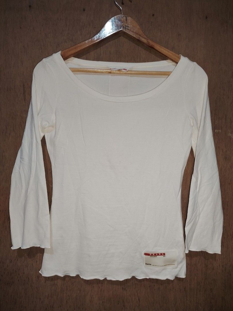 Prada Challenge 2003 White Long Sleeve Top (Category: Longsleeves) located in Roxas, Palawan. Submitted by act_thrift_palawan (Listing ID 1470286070, Image 1). Description: - Brand: Prada Challenge (2003 archive) - Color: White with red back stripe detail - Style: Long-sleeve top with scoop neckline - Details: Woven Prada patch at the lower front hem with name tag line, and Prada red neck branding - Fit/Sizing: Chest and waist measurements shown 