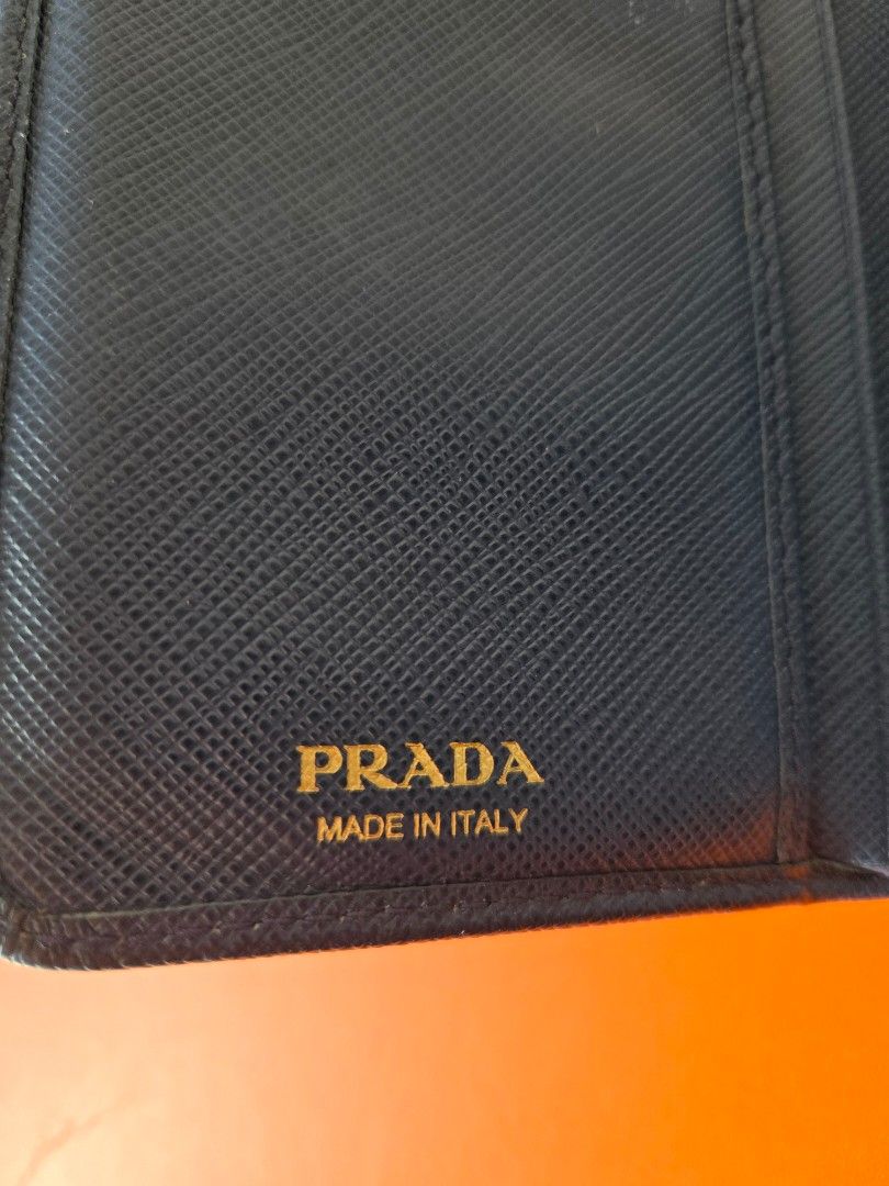 Auth Prada Wallet (Category: Luxury Bags & Wallets) located in Manila. Submitted by luxtimeless (Listing ID 1470160271, Image 3). Description: - Brand: Prada 2 Fold Wallet - Material: Saffiano leather - Color: Dark blue with gold-tone hardware - Closure: Snap closure strap on top flap - Interior: Card slots, bill compartments, and a zippered coin pocket with two main sections - Authenticity: Prada 'Made in Italy' stamp inside - Condition: Noticea