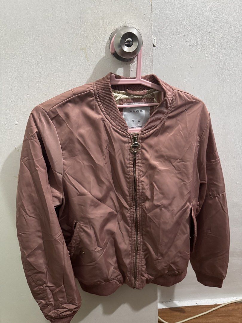 Pull&Bear Pink Bomber Jacket Size M (Category: Coats, Jackets and Outerwear) located in Manila. Submitted by nicefinds (Listing ID 1470286235, Image 1). Description: - Brand: Pull&Bear - Style: Lightweight bomber jacket - Color: Dusty pink with golden inner lining - Size: EUR M / MEX 28 - Closure: Front zipper with round ring pull - Pockets: Side pockets with snap buttons - Details: Ribbed collar, cuffs, and hem - Origin: Made in Indonesia.