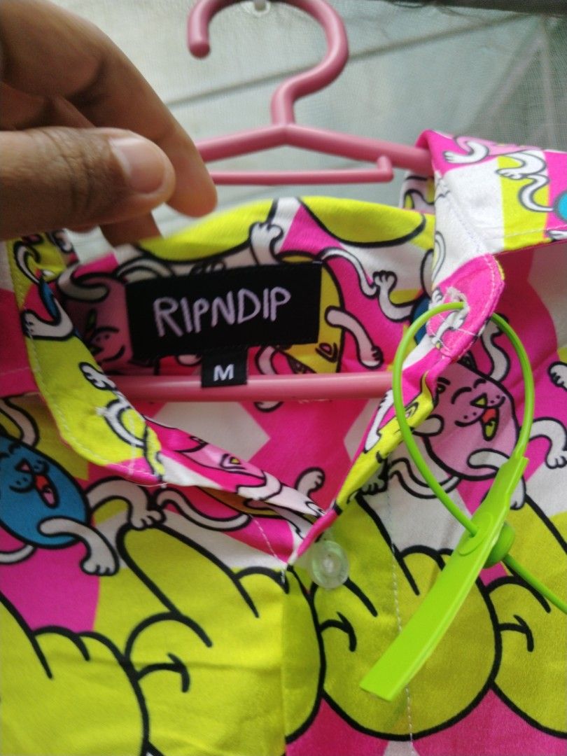 RIPNDIP aop button down (Category: Tshirts & Polo Shirts ) located in Legazpi City. Submitted by genobecollectives (Listing ID 1470206078, Image 3). Description: RIPNDIP aop 880 free ship medium -large 22 x 29 - Style: Short-sleeve button-down shirt - Design: Neon pink, yellow, and white checkerboard with melting cat graphics and hand signs - Size: Medium (tag on collar) - Material: 100% polyester - Condition: Good, includes wash tag with care in