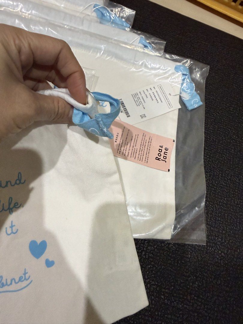 Roan & Jane White Drawstring Pouch Bag (Category: Purses & Pouches) located in Mandaue City. Submitted by erin_grace (Listing ID 1470166129, Image 3). Description: - Brand: Roan & Jane - Material: White canvas with blue handles and drawstring closure - Front Design: 'Pretty things inside' in black text - Back Design: Inspirational quote 'You do not find the happy life. You make it', blue hearts, and Secondary Cabinet text - Condition: Brand new, 