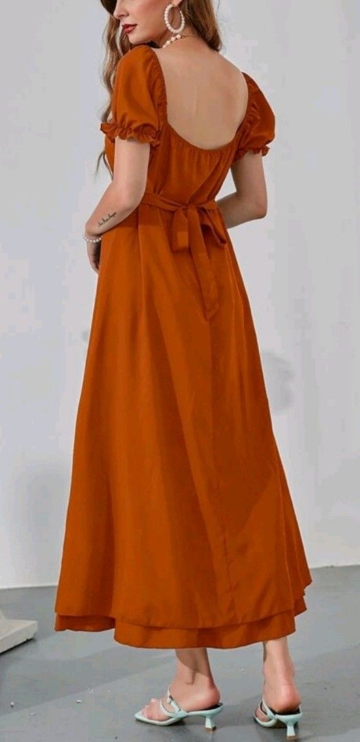 Rust Orange Midi Dress with Puff Sleeves (Category: Dresses) located in Manila. Submitted by gracjam_27 (Listing ID 1470262312, Image 2). Description: - Color: Rust orange - Style: Midi dress with A-line skirt and layered hemline - Details: Short puff sleeves with ruffled cuffs, square neckline front and back - Fit: Fitted bodice with gathered waist and adjustable tie-back belt - Fabric: Smooth, warm earth-tone material - Versatility: Easy to pai