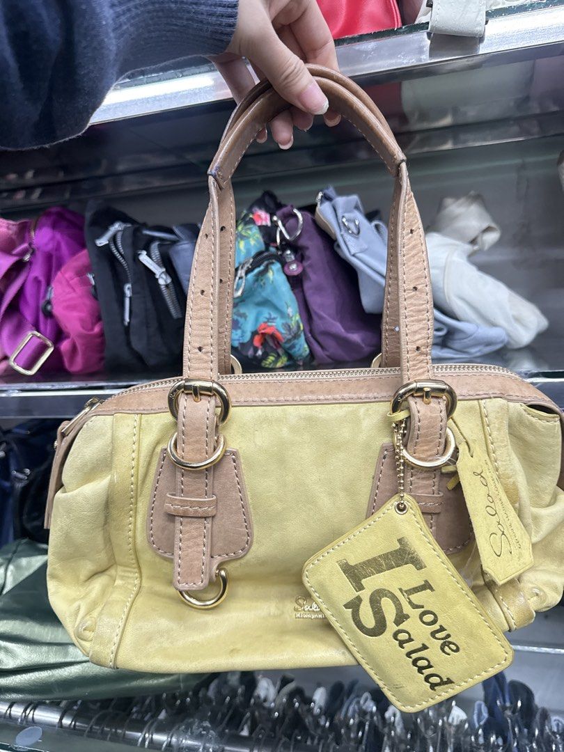 Salad Yellow Leather Handbag (Category: Luxury Bags & Wallets) located in Abucay. Submitted by fastlion.584bdf (Listing ID 1470268658, Image 1). Description: - Brand: Salad - Material: Yellow leather with tan leather handles and trim - Hardware: Gold-tone throughout - Closure: Secure zip top - Extras: Original 'I Love Salad' hanging tag and brand charm included - Design: Compact size with sturdy double handles and front buckle accents.