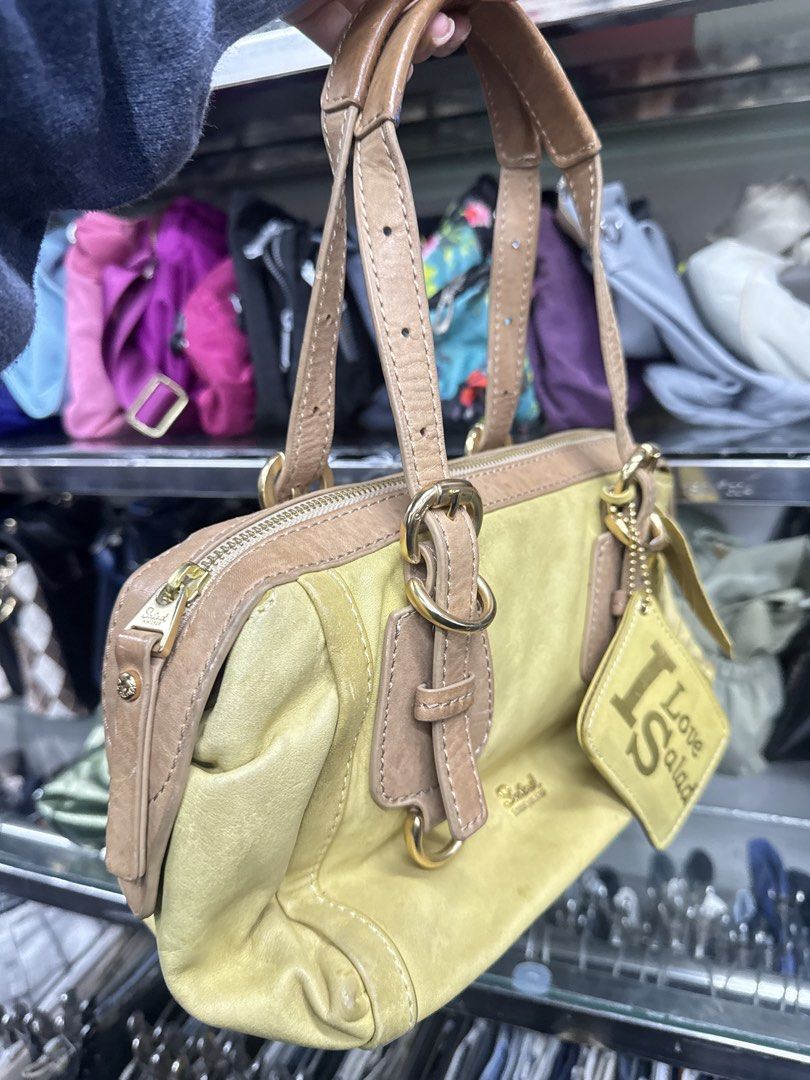 Salad Yellow Leather Handbag (Category: Luxury Bags & Wallets) located in Abucay. Submitted by fastlion.584bdf (Listing ID 1470268658, Image 2). Description: - Brand: Salad - Material: Yellow leather with tan leather handles and trim - Hardware: Gold-tone throughout - Closure: Secure zip top - Extras: Original 'I Love Salad' hanging tag and brand charm included - Design: Compact size with sturdy double handles and front buckle accents.