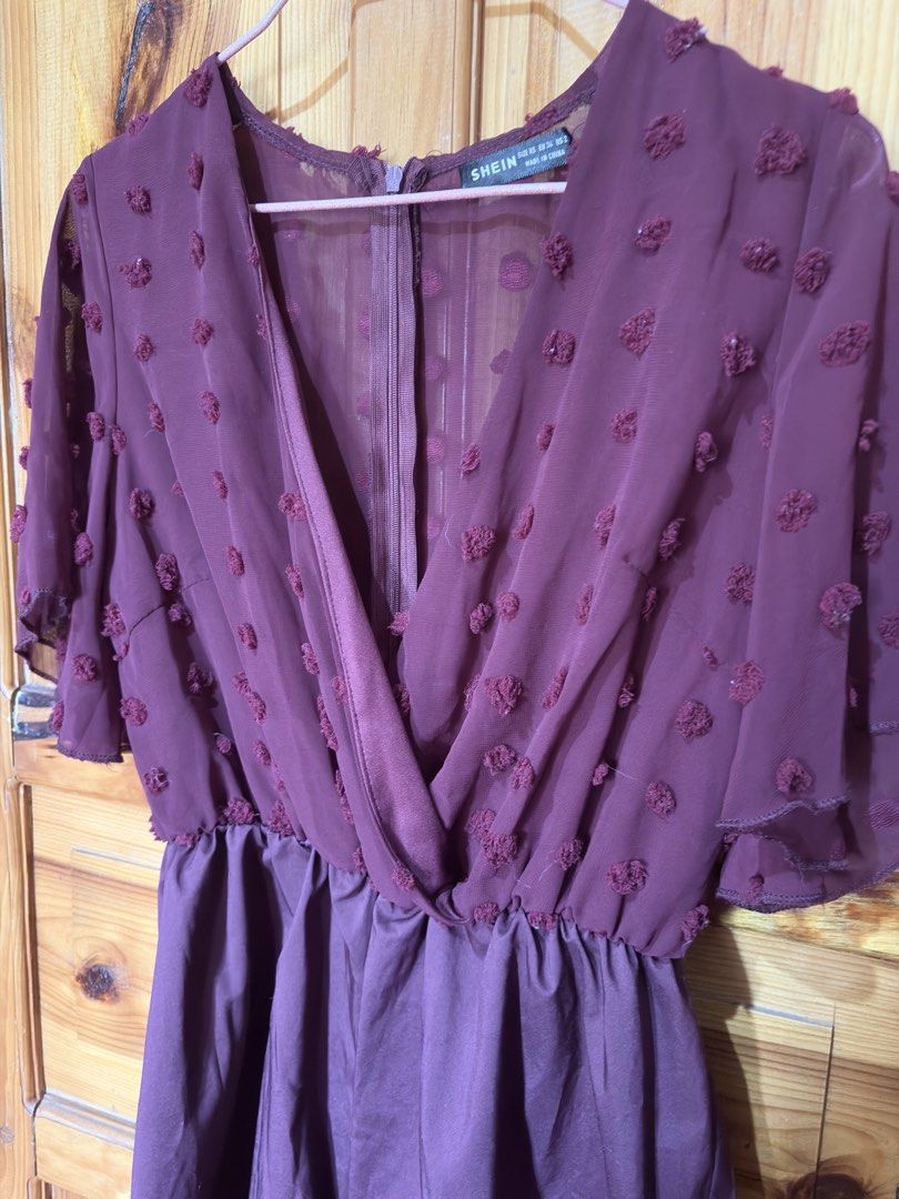 SHEIN Burgundy Dot Chiffon Romper Size XS (Category: Rompers) located in Baguio. Submitted by declutterbycys (Listing ID 1470180320, Image 2). Description: - Brand: SHEIN - Size: XS (EU 34, US 2) - Color: Burgundy - Design: V-neck crossover front with cute flutter sleeves - Details: Sheer dotted mesh top with back zip closure and solid lower half - Fabric: Lightweight and comfortable - Occasion: Perfect for casual outings or dates.