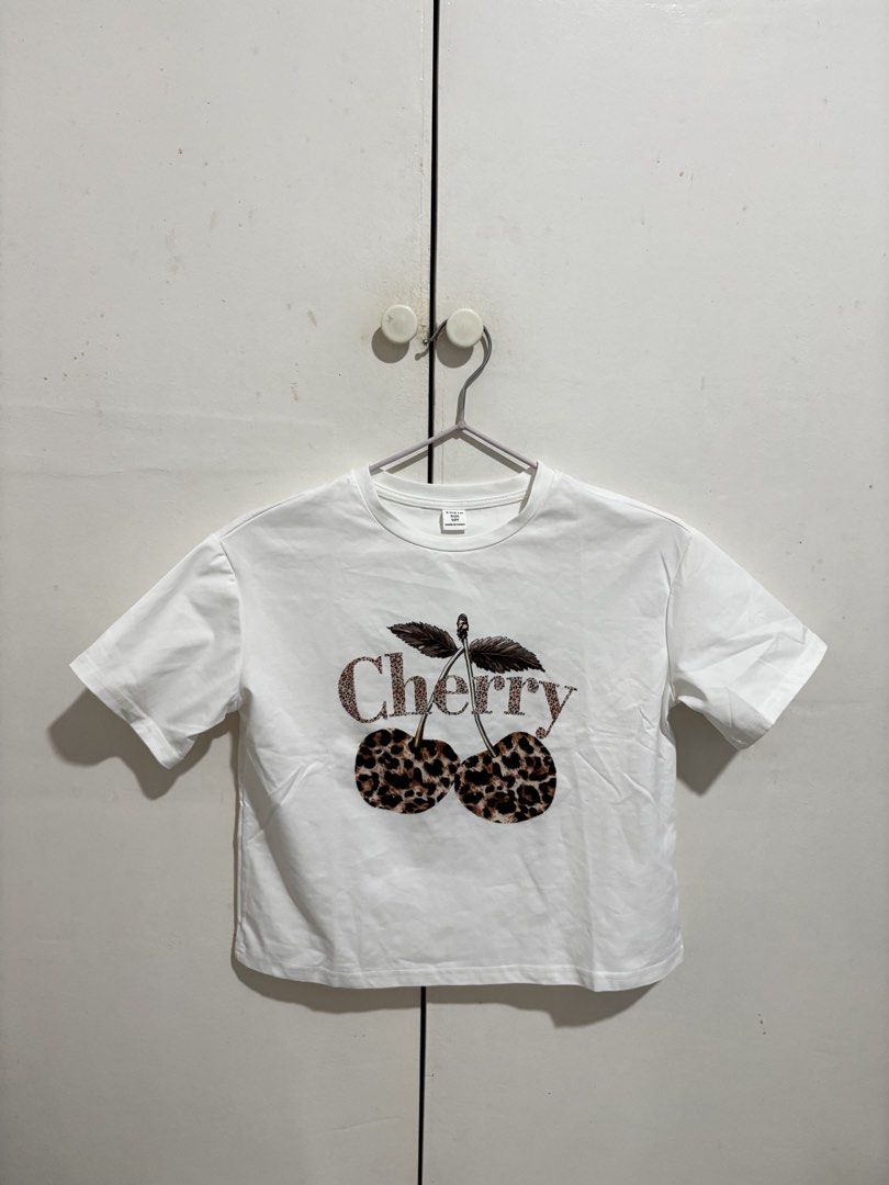SHEIN Leopard Cherry Print White Crop T-Shirt (Category: Shirts) located in Manila. Submitted by dianafayesimbre (Listing ID 1470266494, Image 3). Description: - Size: 10Y on tag but fits xs to medium - Design: White tee with trendy leopard print cherry graphic - Fit: Cropped and short-sleeved - Material: Soft, comfortable cotton - Condition: Brand new - Styling: Easy to pair with your favorite shorts or jeans for a casual look.