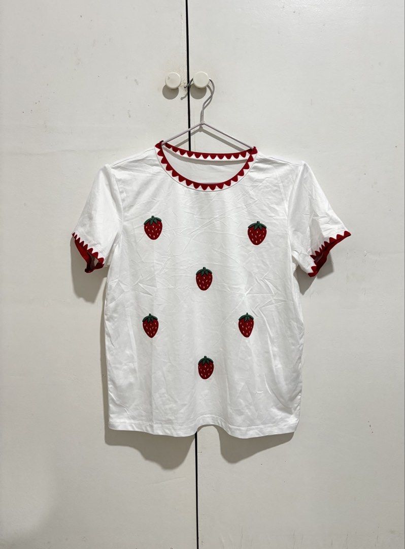 Shein White strawberry shirt (Category: Shirts) located in Manila. Submitted by dianafayesimbre (Listing ID 1470269508, Image 2). Description: - Color: Crisp white with red scalloped trim - Design: Embroidered strawberry pattern on the front, plain back - Fit: Short-sleeve crew neck, casual everyday style - Styling: Great to pair with high-waisted denim or skirts - Condition: Brand new - Size 11Y on tag but fits xs to semi L.