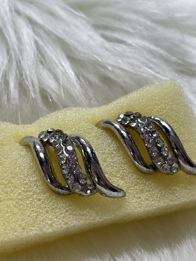 Silver Rhinestone Swirl Stud Earrings (Category: Earrings) located in San Juan City. Submitted by redrosierose (Listing ID 1470256497, Image 2). Description: - Silver-toned metal swirl earrings - Decorated with a center stripe of clear rhinestone crystals - Secure post back closure with butterfly backs - Modern curved design for a chic look - Versatile accessory for both daily wear and formal events - Clean condition, guaranteed no missing stones