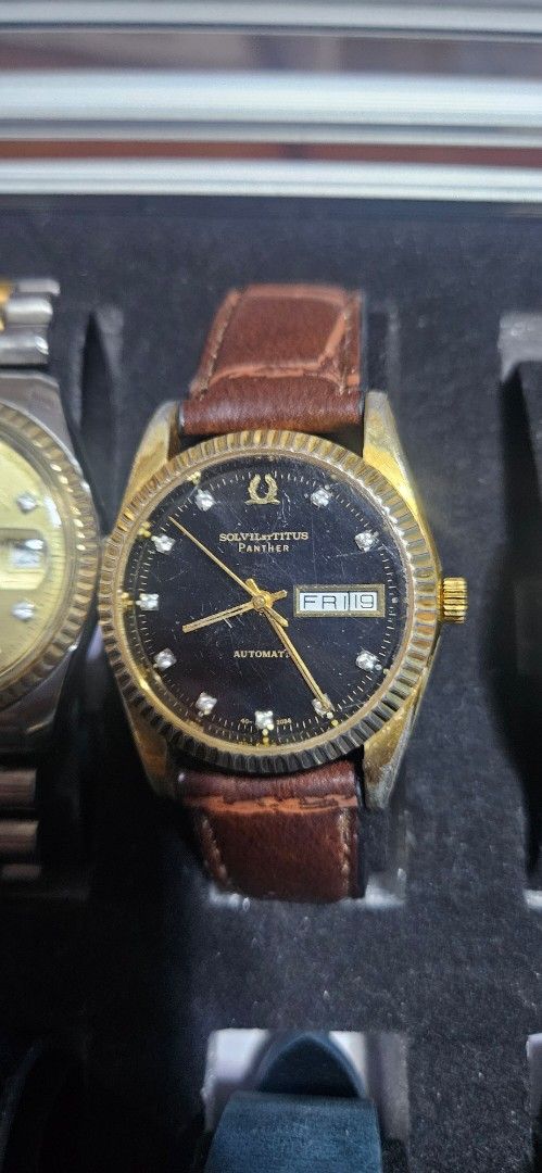 Solvil et Titus Panther Automatic Watch (Category: Men's Watches) located in Santa Maria. Submitted by rommelmateo (Listing ID 1470215852, Image 1). Description: - Brand/Model: Solvil et Titus Panther Automatic Watch (Vintage Collection) - Dial & Bezel: Black dial with rhinestone hour markers and gold tone fluted bezel - Features: Day and date window at the 3 o'clock position - Strap: Fitted brown leather strap - Condition: Noticeable scratches o