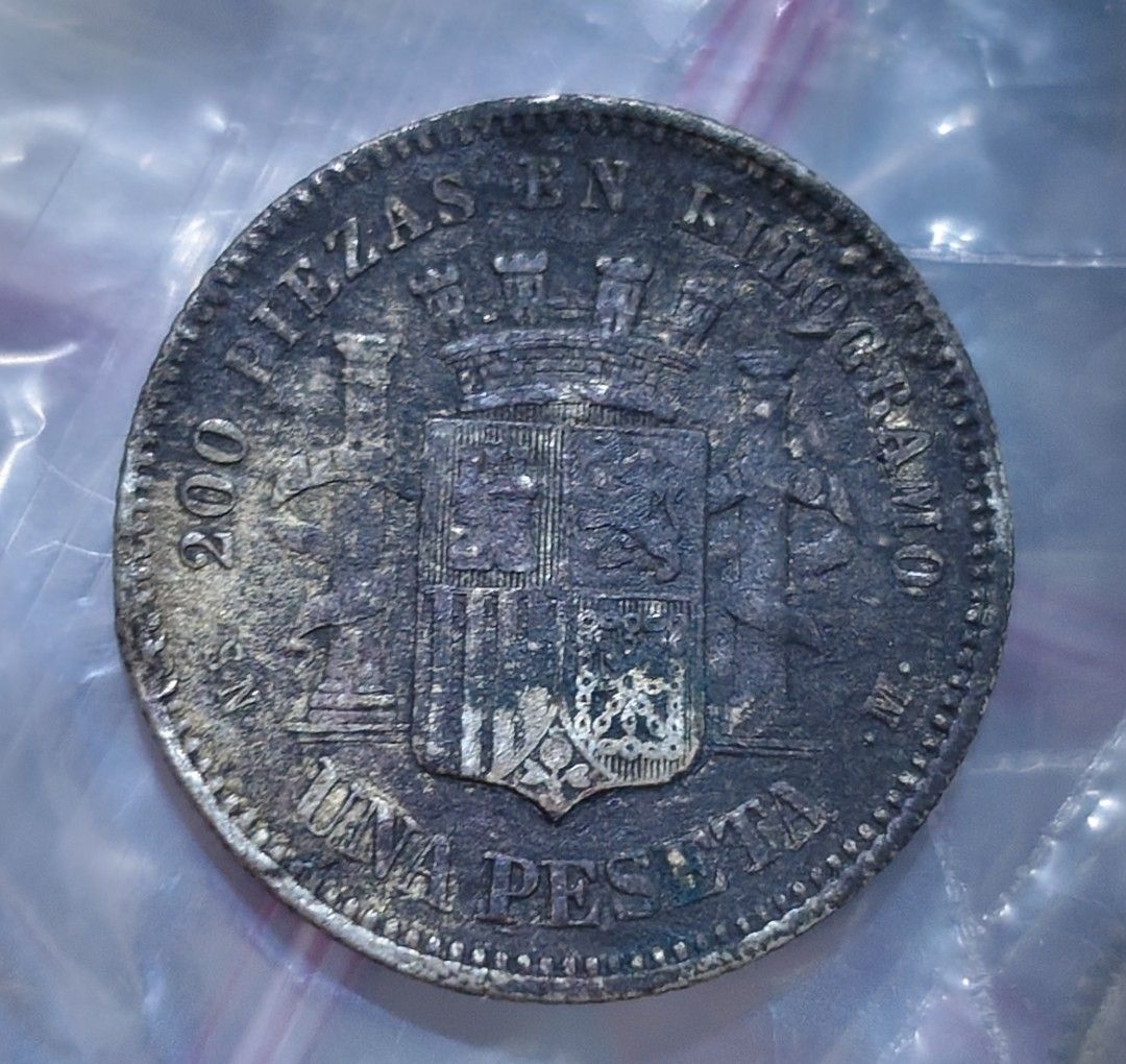 Spain 1870 1 Peseta Coin (Category: Currency) located in Taguig. Submitted by ezekiel103 (Listing ID 1470222167, Image 2). Description: - Item: 1870 Spanish 1 Peseta Coin - Obverse: Features the seated allegory of Hispania holding an olive branch with the date 1870 - Reverse: Displays the Spanish coat of arms flanked by pillars, with '200 PIEZAS EN KILOGRAMO' and 'UNA PESETA' - Condition: Heavy tarnish, natural toning, and surface wear consistent