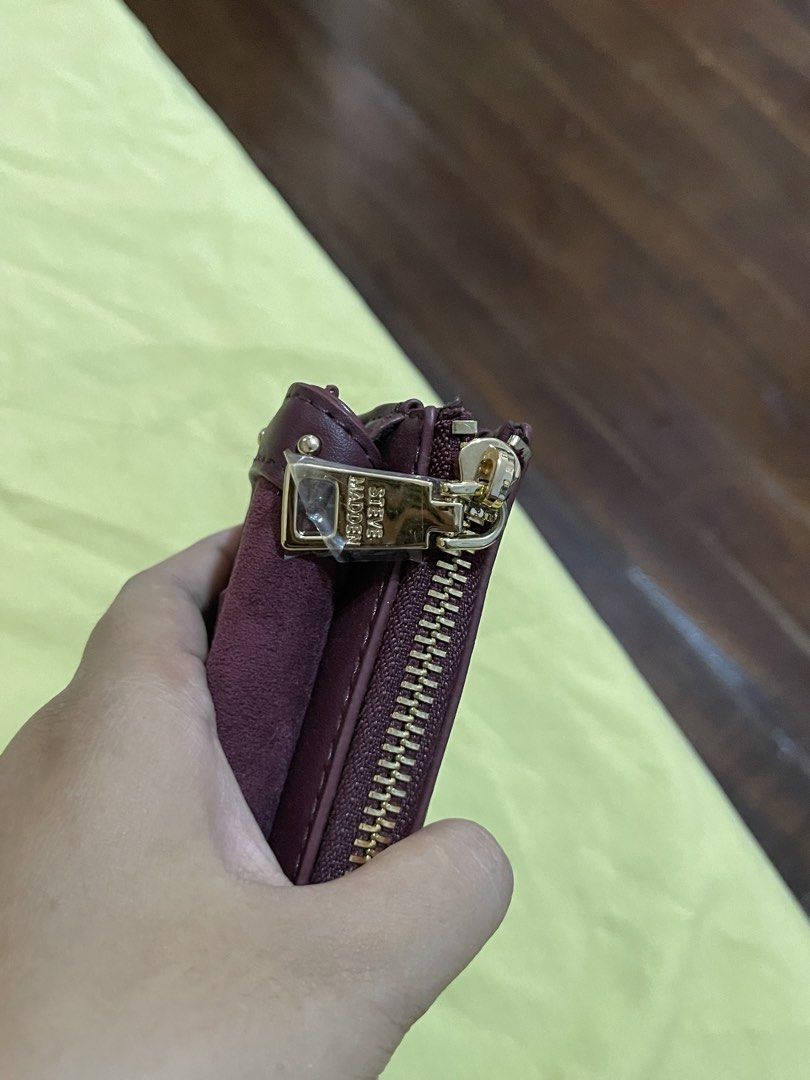 Steve Madden Maroon Wallet (Category: Wallets & Card holders) located in Mabitac. Submitted by aquillareyes_ (Listing ID 1470212792, Image 3). Description: Steve Madden maroon wallet with gold hardware and studded details. Flap and zipper closure. Interior zip coin pocket, cash compartment, and multiple card slots. Branded fabric lining inside. Protective plastic still attached to the zipper pull. Clean interior and exterior..