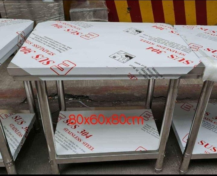 SUS 304 Stainless Steel Kitchen Work Table 80x60x80cm (Category: Tables & Sets) located in Manila. Submitted by mightytiger_4bb6fd (Listing ID 1470217622, Image 1). Description: - Material: Premium SUS 304 grade stainless steel - Dimensions: 80cm (L) x 60cm (W) x 80cm (H) - Design: 2 tiers with a sturdy lower shelf for extra storage - Condition: Brand new with protective plastic film (peel off before use) - Ideal for: Kitchens, garages, workshops