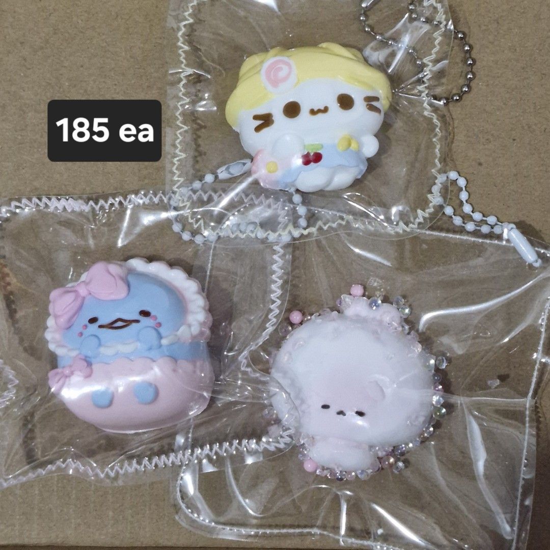 Taba Squishy (Category: Character Goods) located in Manila. Submitted by mochacchi (Listing ID 1470267723, Image 1). Description: - Price: ₱185 each - Condition: Brand new, sealed in original packaging - Attachment: Includes a cute beaded chain - Available Designs: * Yellow cat figure * Blue creature with a pink bow * White fluffy character with tiny beads.