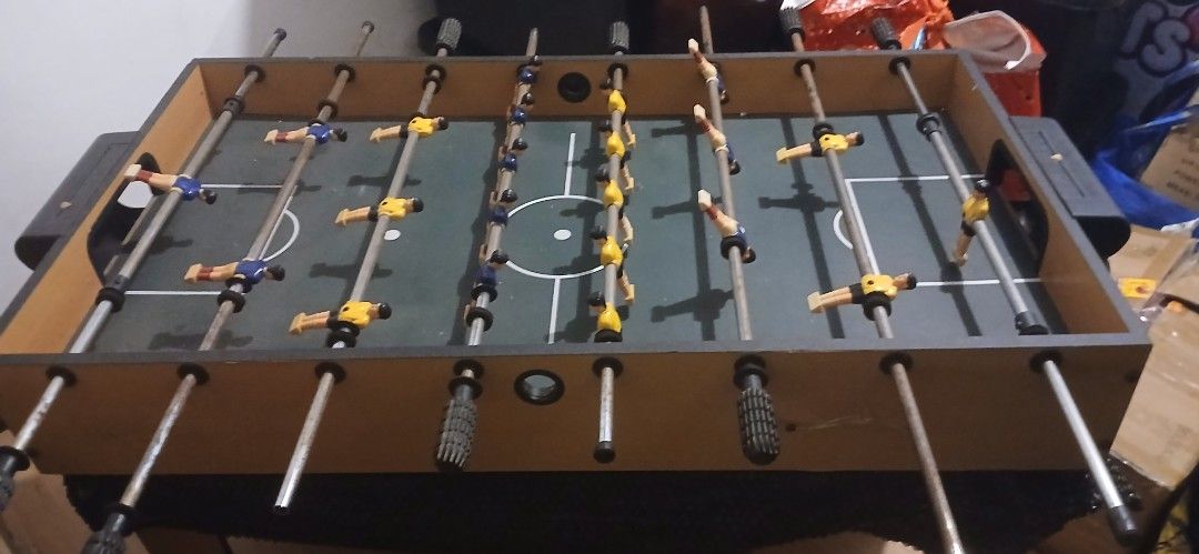 Tabletop Foosball Table with Blue and Yellow Players (Category: Board Games & Puzzles) located in San Juan City. Submitted by frugalmomph (Listing ID 1470170334, Image 2). Description: - Type: Mini tabletop foosball game - Design: Wooden finish cabinet with green pitch markings - Components: Metal rods, plastic handles, and yellow/blue players - Condition: Fully assembled and ready to play, with some light scuffs from normal use - Perfect for: Ga