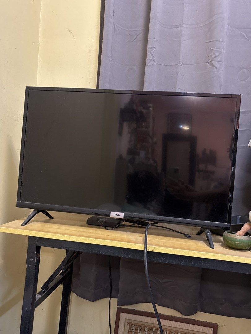 TCL SMART TV 32-inch Television (Category: TV) located in Malabon City. Submitted by luxgoals (Listing ID 1470188311, Image 3). Description: - Brand/Model: TCL 32S5200 SMART TV - Screen Size: 32 inches - Color/Design: Clean black finish with matching bezel and sturdy stand legs - Connectivity: Standard ports on the back panel including HDMI - Power: 100-240V, comes with an attached power cable - Condition: Excellent, sits steadily on any desk or 