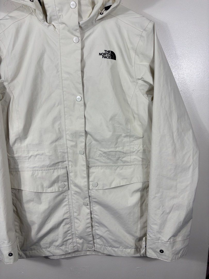 The North Face White Hooded Rain Jacket (Category: Coats, Jackets and Outerwear) located in Manila. Submitted by south_finds (Listing ID 1470220841, Image 3). Description: - Brand: The North Face - Color: Clean Off-White with Black Embroidered Logo - Material: Lightweight, weatherproof fabric - Closure: Full zip with snap button storm flap - Features: Drawstring hood, adjustable cuffs, and two large front flap pockets - Condition: Excellent / Rea