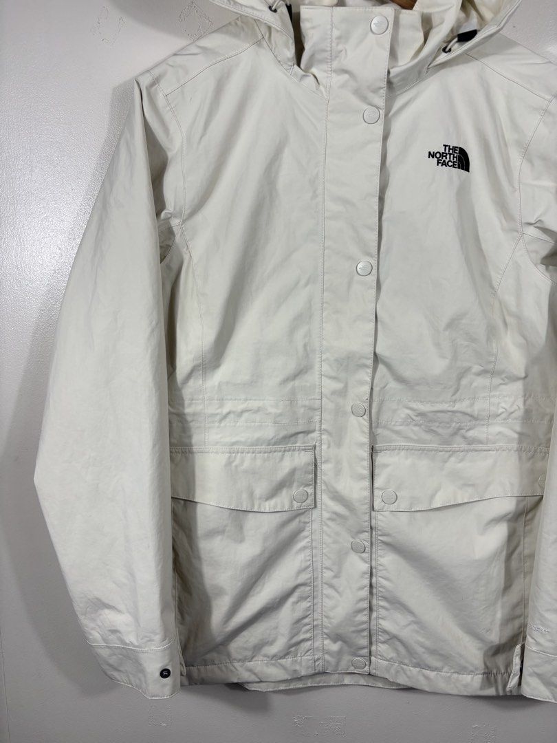 The North Face White Hooded Rain Jacket (Category: Coats, Jackets and Outerwear) located in Manila. Submitted by south_finds (Listing ID 1470220841, Image 2). Description: - Brand: The North Face - Color: Clean Off-White with Black Embroidered Logo - Material: Lightweight, weatherproof fabric - Closure: Full zip with snap button storm flap - Features: Drawstring hood, adjustable cuffs, and two large front flap pockets - Condition: Excellent / Rea