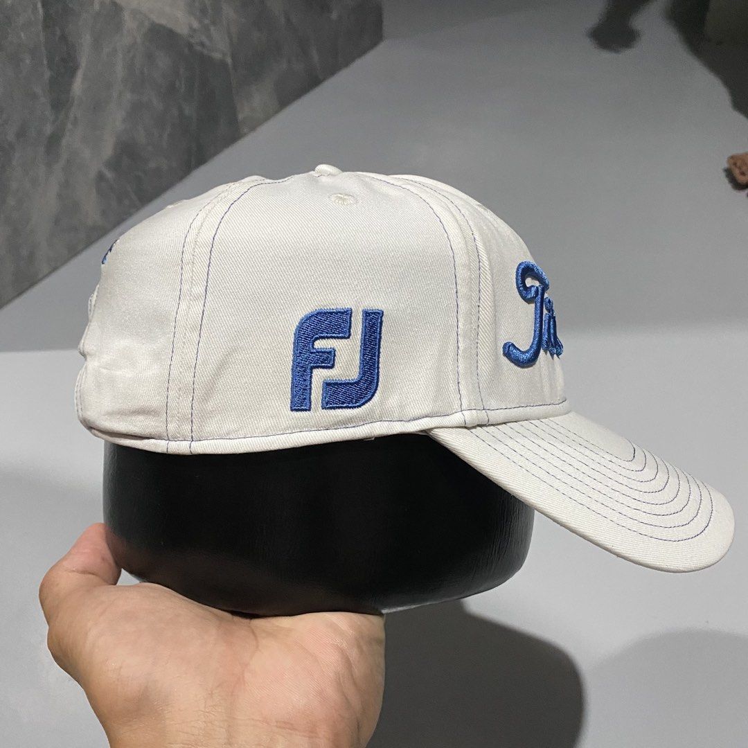Titleist Pro V1 Golf Cap White Blue Adjustable (Category: Caps & Hats) located in Villasis. Submitted by thriftngrind (Listing ID 1470286821, Image 3). Description: - Authentic Titleist golf hat in clean white fabric - Stylish blue embroidered lettering on the front - Pro V1 logo on one side and FJ logo on the other - Titleist text embroidered on the back strap - Structured brim with contrast blue stitching - Adjustable metal buckle clasp with en