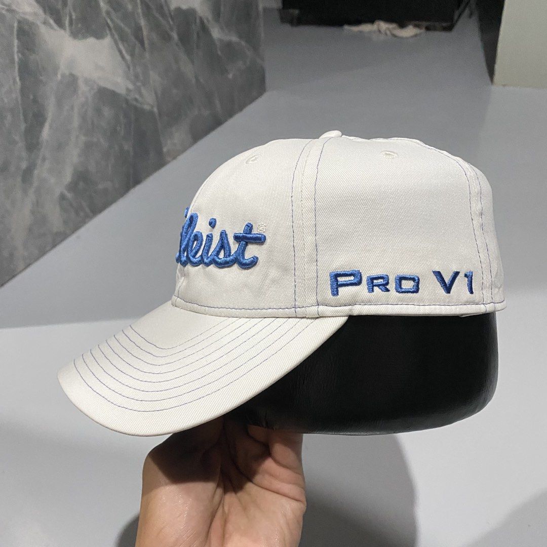 Titleist Pro V1 Golf Cap White Blue Adjustable (Category: Caps & Hats) located in Villasis. Submitted by thriftngrind (Listing ID 1470286821, Image 2). Description: - Authentic Titleist golf hat in clean white fabric - Stylish blue embroidered lettering on the front - Pro V1 logo on one side and FJ logo on the other - Titleist text embroidered on the back strap - Structured brim with contrast blue stitching - Adjustable metal buckle clasp with en