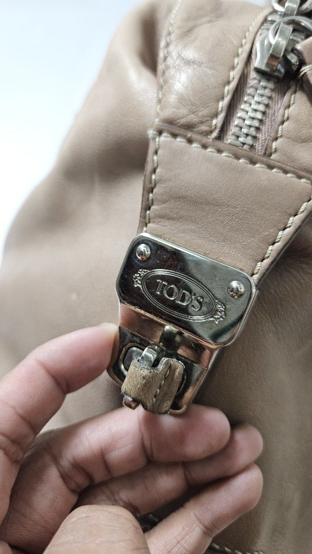 Tod's D Styling Bauletto Bag (Category: Luxury Bags & Wallets) located in Alfonso. Submitted by jbcamet (Listing ID 1470267393, Image 2). Description: - Brand: Tod's - Material: Taupe leather with fabric lining - Hardware: Silver-tone with branded metal side closure - Features: Double top handles, protective bottom feet, interior serial number tag - Condition Notes: Exterior has scuffs and wear from use; interior fabric lining shows notable dirt 