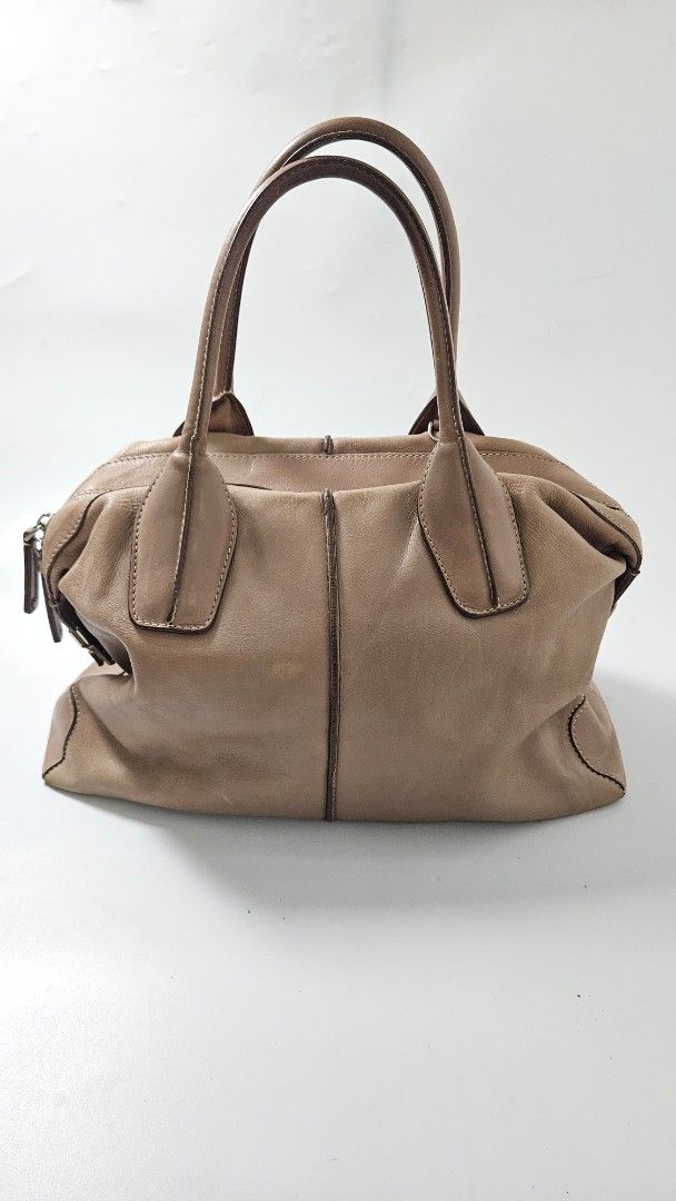 Tod's D Styling Bauletto Bag (Category: Luxury Bags & Wallets) located in Alfonso. Submitted by jbcamet (Listing ID 1470267393, Image 1). Description: - Brand: Tod's - Material: Taupe leather with fabric lining - Hardware: Silver-tone with branded metal side closure - Features: Double top handles, protective bottom feet, interior serial number tag - Condition Notes: Exterior has scuffs and wear from use; interior fabric lining shows notable dirt 