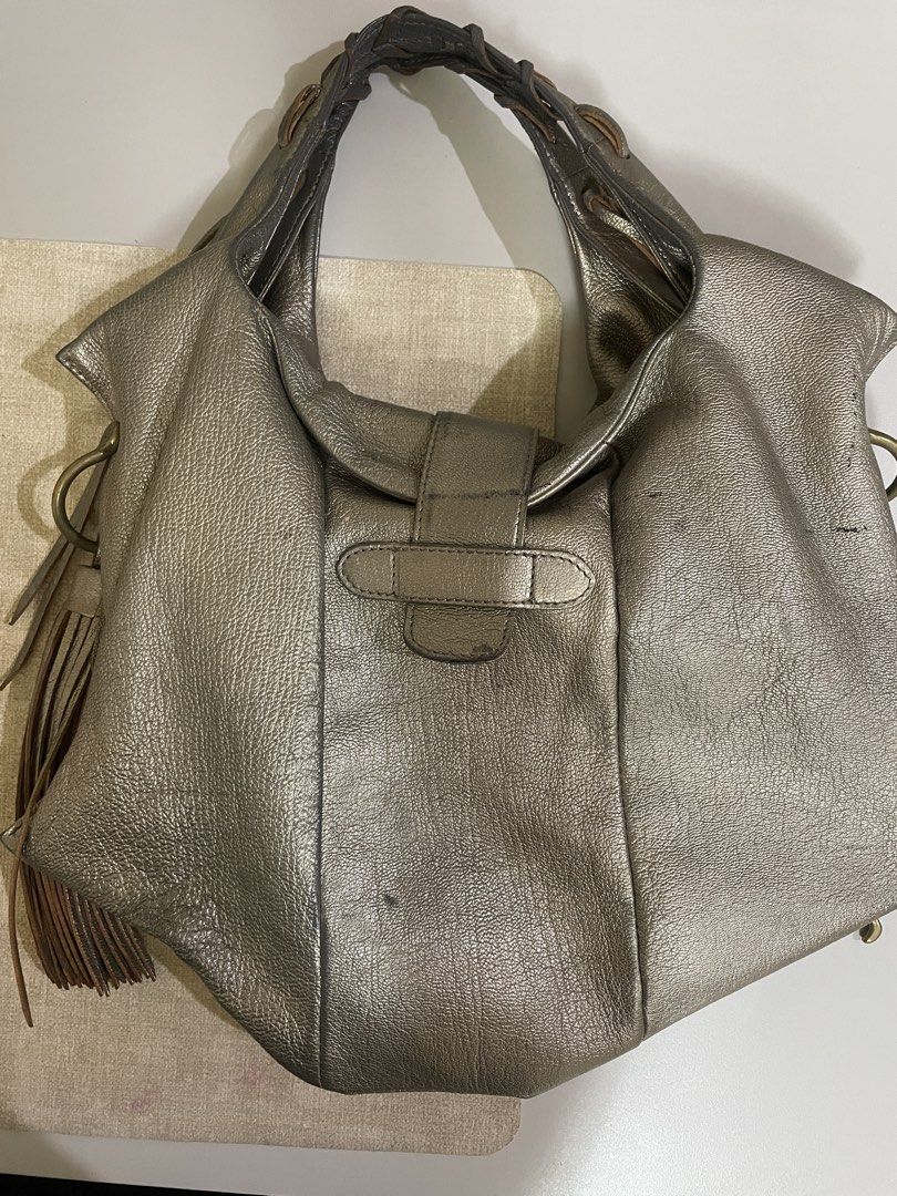 Toff & Loadstone Metallic Silver Leather Shoulder Bag (Category: Shoulder Bags) located in Calamba. Submitted by melibear (Listing ID 1470310772, Image 2). Description: - Brand: Toff & Loadstone - Color/Material: Metallic silver leather with gold-tone hardware - Handles & Accents: Braided top handle, stylish side fringe tassels, and front structured buckle strap closure - Pockets: Exterior zip pocket, plus interior slip pockets and one zippered c
