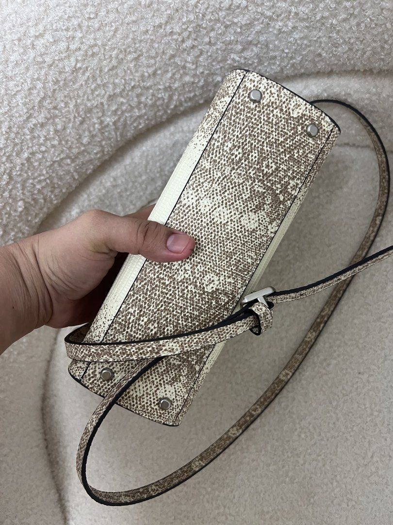 Tory Burch Eleanor Top Handle Bag (Category: Cross-body Bags) located in Abulug. Submitted by jamiecammie (Listing ID 1470273503, Image 3). Description: - Brand: Tory Burch - Design: Cream and brown snakeskin print with silver hardware and iconic T logo clasp - Versatility: Includes a top handle and a matching adjustable crossbody strap - Interior: Clean white lining with a convenient card pocket slot - Protection: Bottom features four metal feet