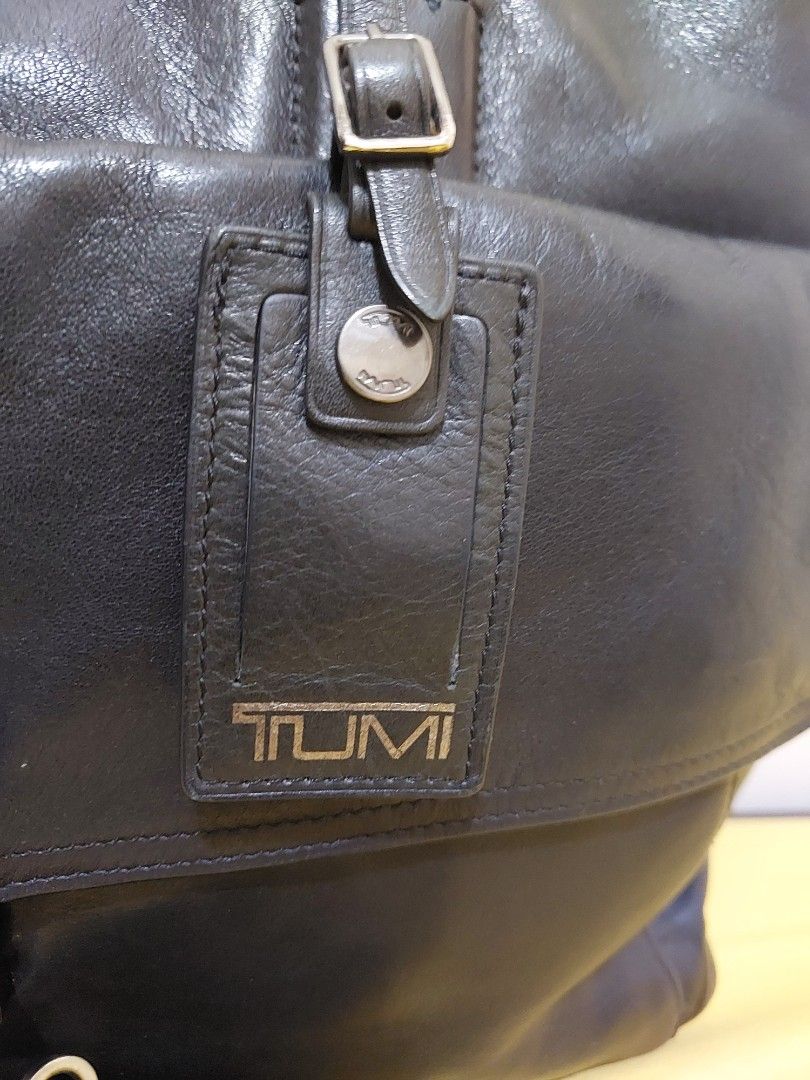 TUMI Black Leather Briefcase Laptop Bag with Strap (Category: Briefcases) located in Malabon City. Submitted by jullie_bag_shop (Listing ID 1470271511, Image 2). Description: - Brand: TUMI - Material: Genuine Black Leather - Features: Dual top handles, detachable shoulder strap, and front flap pocket with metal buckle closure - Interior: Multiple compartments with striped lining, zipped pockets, and card slots - Condition: Sturdy professional wor