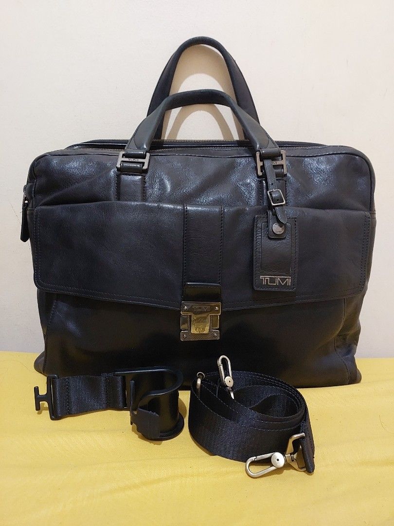 TUMI Black Leather Briefcase Laptop Bag with Strap (Category: Briefcases) located in Malabon City. Submitted by jullie_bag_shop (Listing ID 1470271511, Image 1). Description: - Brand: TUMI - Material: Genuine Black Leather - Features: Dual top handles, detachable shoulder strap, and front flap pocket with metal buckle closure - Interior: Multiple compartments with striped lining, zipped pockets, and card slots - Condition: Sturdy professional wor