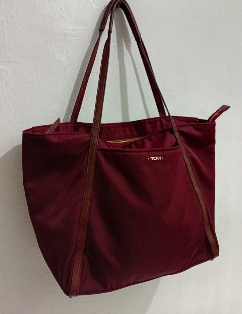 TUMI Voyageur LARGE SHOULDER Q TOTEbag (Category: Luxury Bags & Wallets) located in Manila. Submitted by eriiicaspage (Listing ID 1467043512, Image 1). Description: PreOwned Lightly Used TUMI LARGE VOYAGEUR MAROON NYLON Q TOTE SHOULDER BAG - Color: Burgundy nylon with brown leather straps and gold-tone hardware - Closure: Secure zip-top closure - Exterior: Front slip pocket with signature metal TUMI logo plaque - Interior: Spacious compartment fo