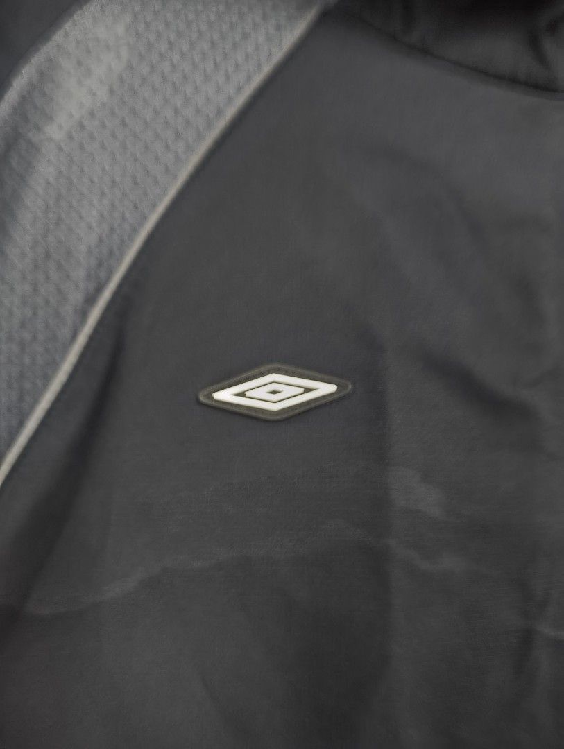 Umbro Quarter-Zip Hooded windbreaker (Category: Coats, Jackets and Outerwear) located in San Pedro. Submitted by madvillainkicks (Listing ID 1470152944, Image 3). Description: Black Umbro quarter-zip hooded windbreaker with grey textured shoulder panels and piping details. Big Umbro branding printed across the front pocket flap. Kangaroo pocket with side zips. Lightweight fabric, good for outdoor workouts or casual wear. Clean interior collar and