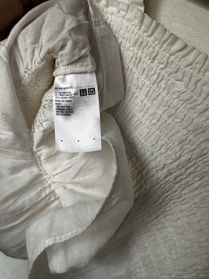Uniqlo White Shirred Top (Category: Sleeveless) located in Manila. Submitted by omelette.12 (Listing ID 1470244410, Image 2). Description: - Brand: Uniqlo - Size: S - Color: White - Material: 100% cotton body (lightweight and breathable) - Design: Stretchy smocked body with cute ruffle straps and hem - Condition/Fit: Super comfy for warm weather, easy to match with high-waisted jeans or skirts.