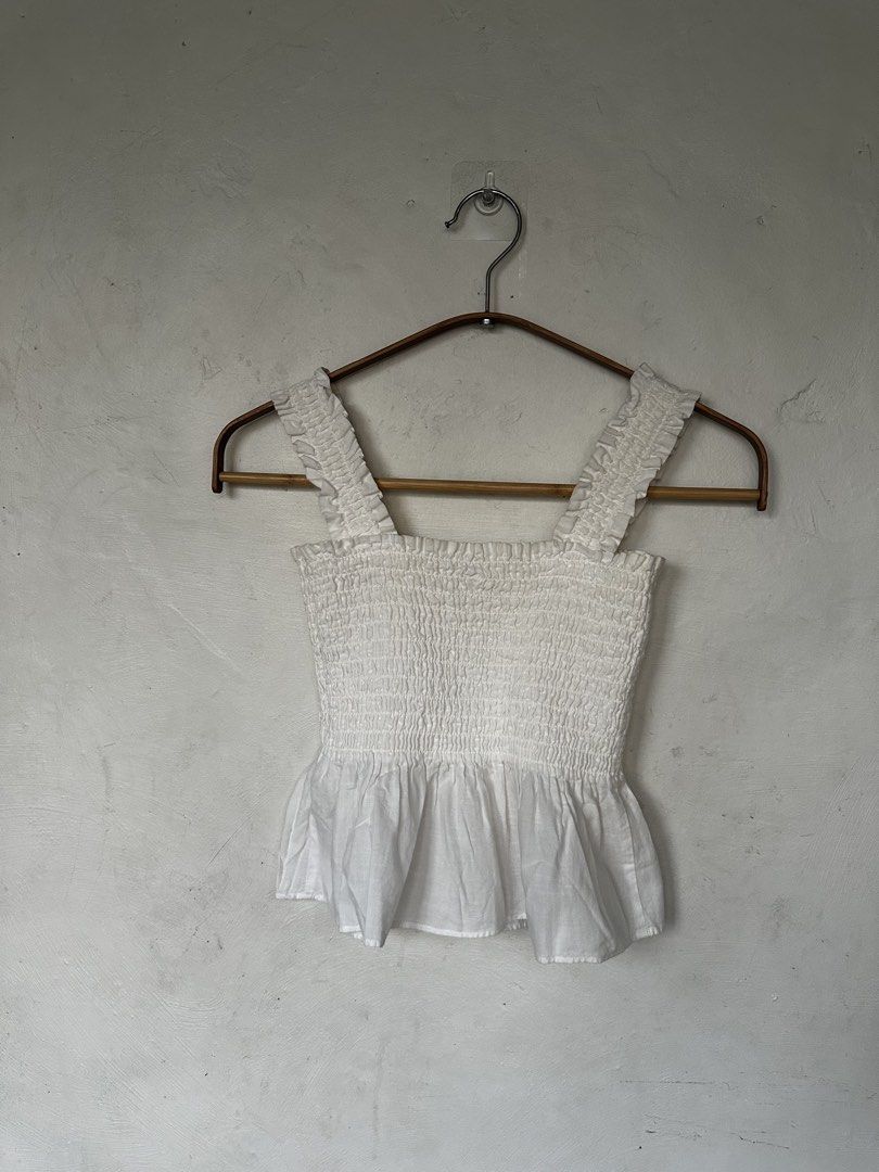 Uniqlo White Shirred Top (Category: Sleeveless) located in Manila. Submitted by omelette.12 (Listing ID 1470244410, Image 1). Description: - Brand: Uniqlo - Size: S - Color: White - Material: 100% cotton body (lightweight and breathable) - Design: Stretchy smocked body with cute ruffle straps and hem - Condition/Fit: Super comfy for warm weather, easy to match with high-waisted jeans or skirts.