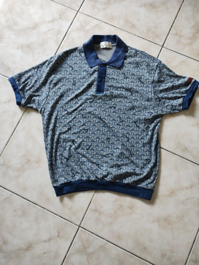 Vintage Adidas Descente Blue Patterned Polo Shirt (Category: Tshirts & Polo Shirts ) located in Imus. Submitted by darylg88358770 (Listing ID 1470156889, Image 1). Description: - Brand: Adidas (Made by Descente, Japan) - Style: Vintage retro sportswear polo shirt - Color/Pattern: Blue and grey patterned fabric with solid blue collar, cuffs, and hem - Features: Short sleeves and button placket neckline - Size: Tagged JASPOM 90-4 (Recommended for h